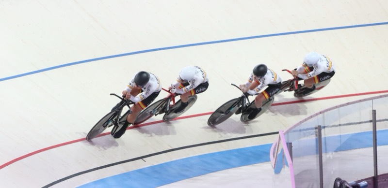Cuarteto femenino de persecución rodando en fila india por el peralte de un velódromo cubierto