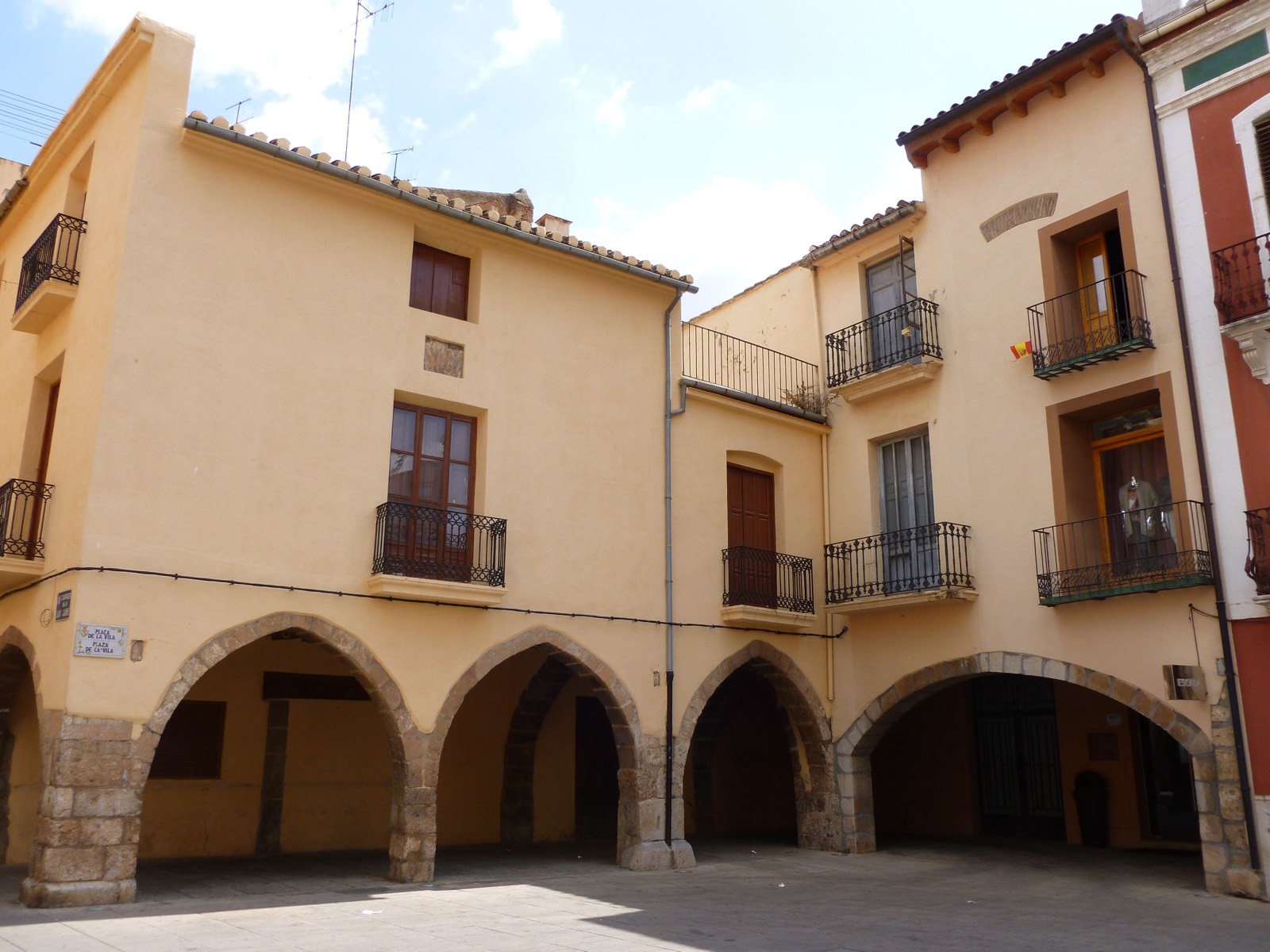 Soportales de piedra y casas de dos plantas con balcones en la plaça de la Vila de Vila-real