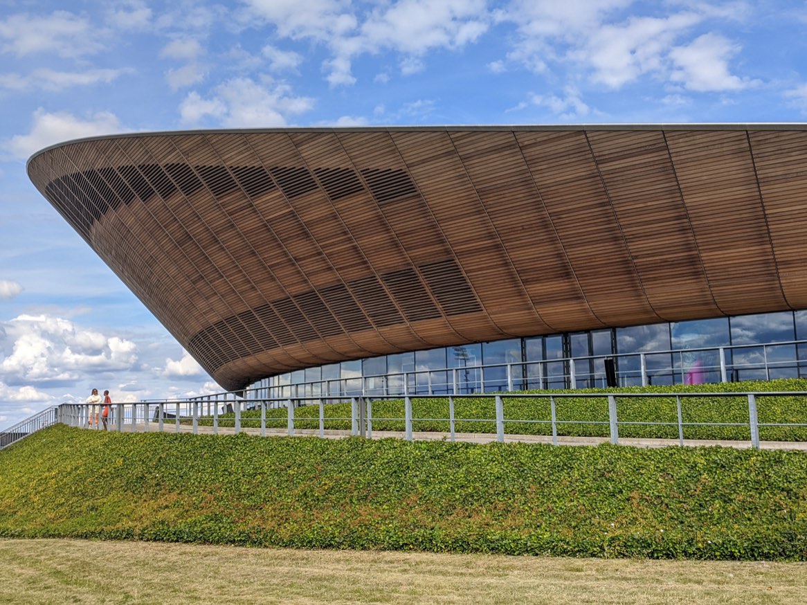 Exterior del velódromo de Londres, con la cubierta curva revestida de listones de madera sobre un talud de hierba